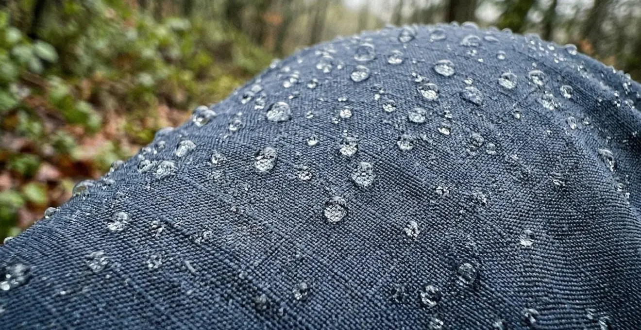 Gros plan sur des gouttes d'eau à la surface d'un textile technique bleu, montrant la texture des fibres absorbantes