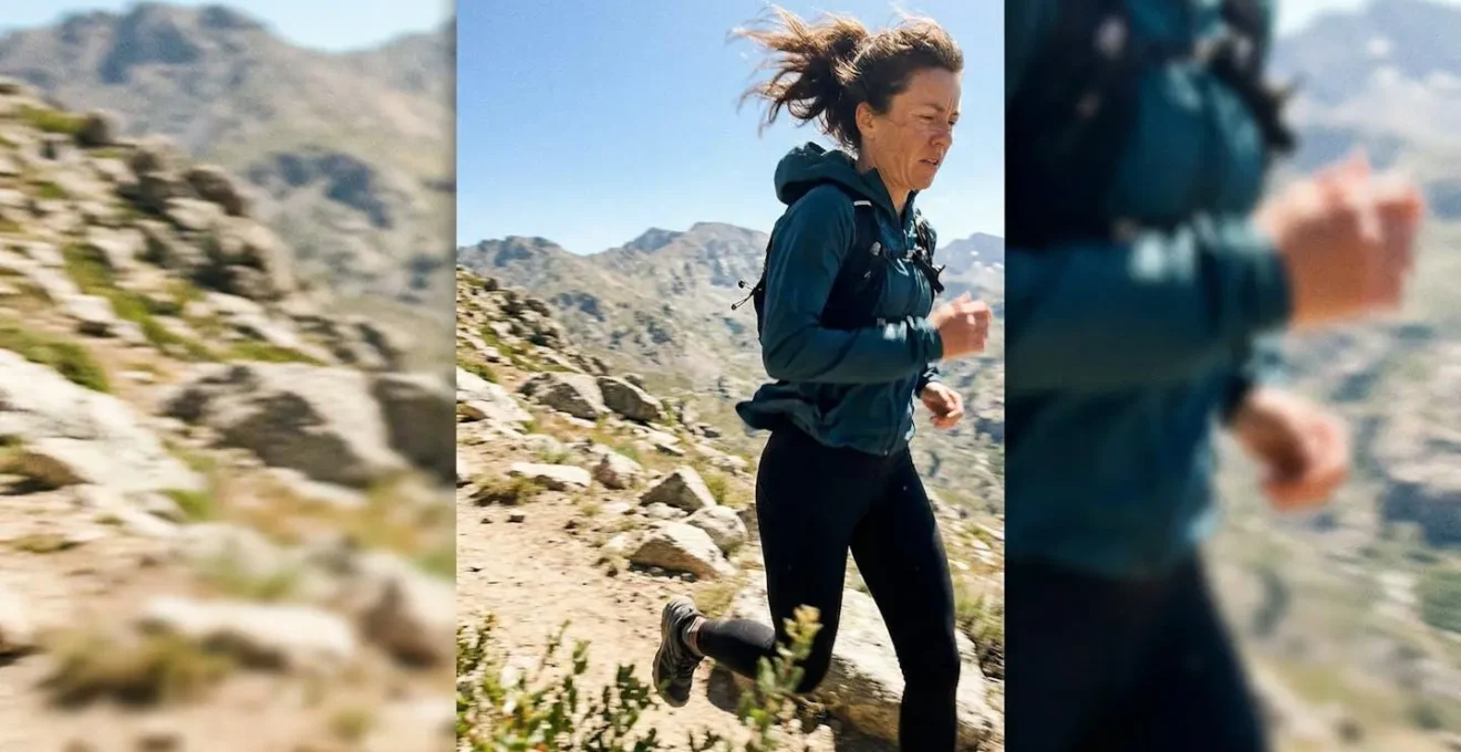 Une personne en mouvement à l'extérieur portant un vêtement technique, cheveux légèrement soulevés par le vent